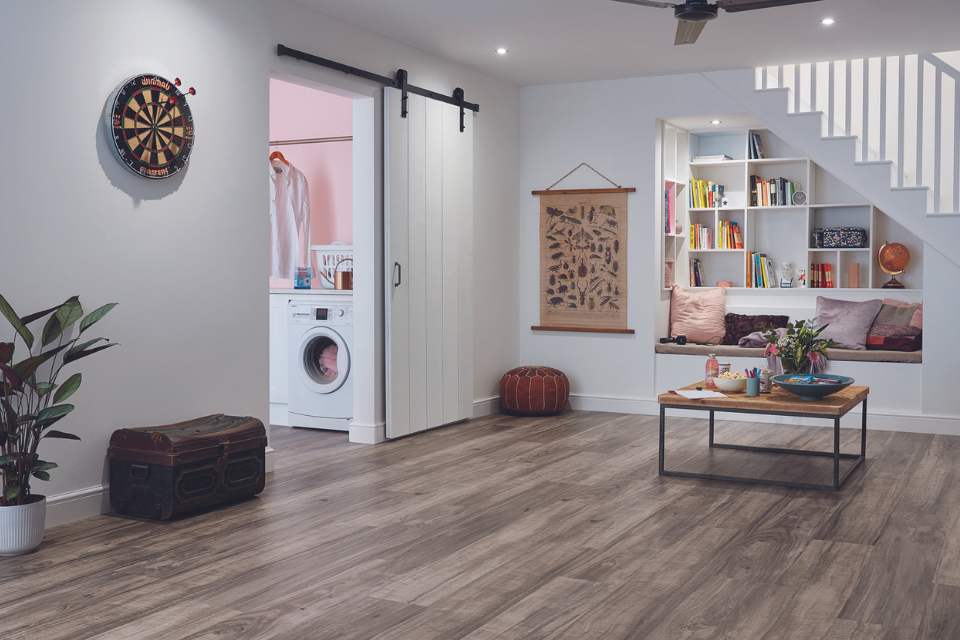 wood look luxury vinyl in finished basement with sliding barn door to laundry room